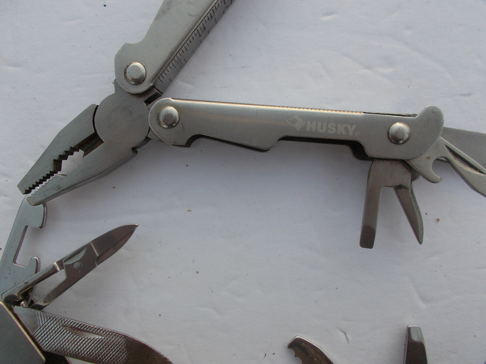 Lot of (2) multi tools – 1 Husky silver color and 1 unbranded silver color